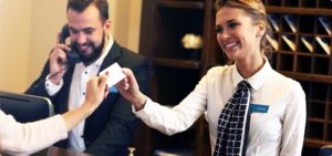 Female Caucasian hotel receptionist handing room key to guest