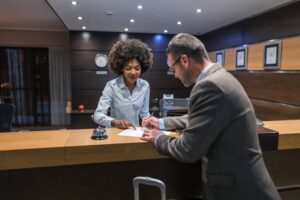 Caucasian male with African American front desk clerk signing papers