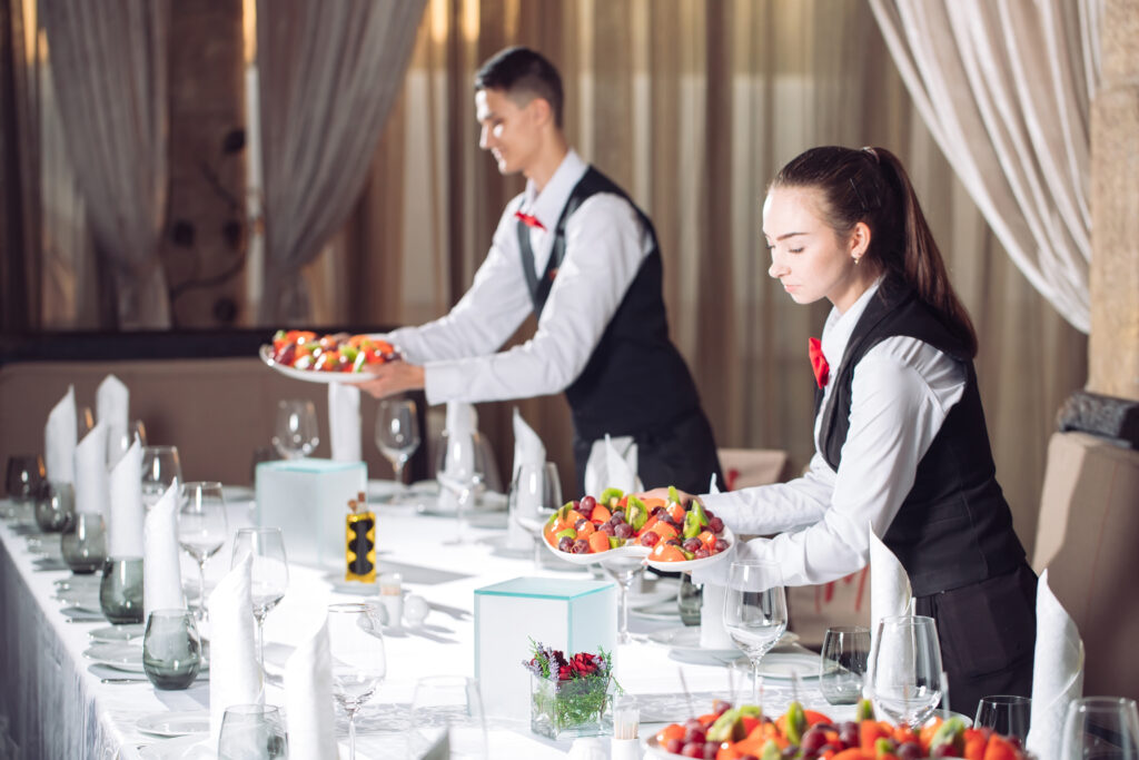 Waiters serving table in the restaurant preparing to receive guests.